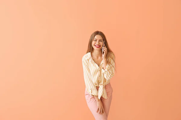Mujer joven y feliz hablando por teléfono móvil en el fondo de color —  Fotos de Stock