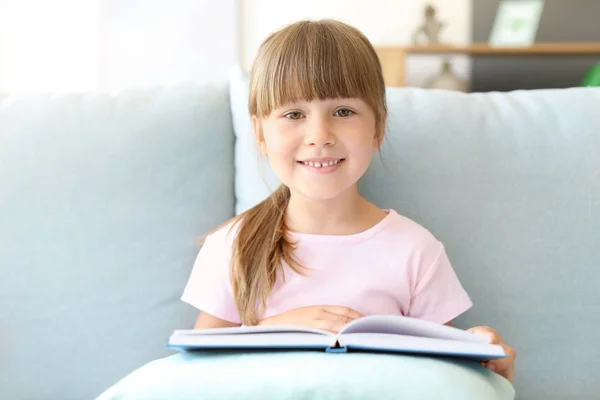 Χαριτωμένο κοριτσάκι διαβάζοντας βιβλίο στο σπίτι — Φωτογραφία Αρχείου