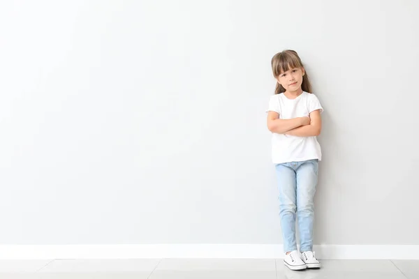 Malá holčička ve stylovém tričku u světlé zdi — Stock fotografie