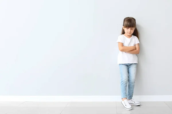 Klein meisje in stijlvolle t-shirt in de buurt van lichte muur — Stockfoto