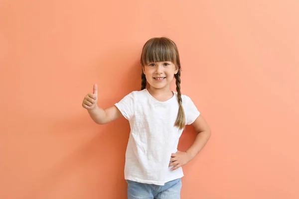 穿着时尚T恤的小女孩在色彩背景上竖起大拇指 — 图库照片
