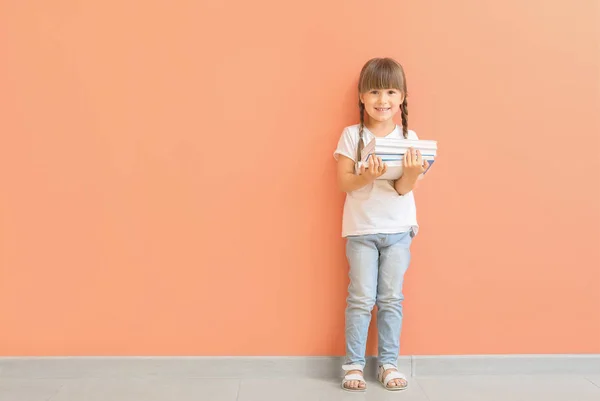 Χαριτωμένο μικρό κορίτσι με τα βιβλία κοντά στο χρώμα τοίχου — Φωτογραφία Αρχείου