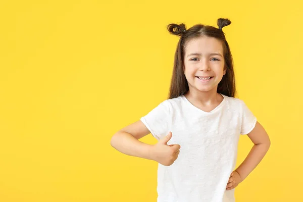 Μικρό κορίτσι με κομψό t-shirt δείχνοντας αντίχειρας στο χρώμα φόντο — Φωτογραφία Αρχείου
