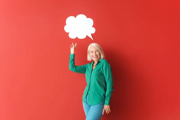 Mature woman with blank speech bubble on color background — Stock Photo, Image