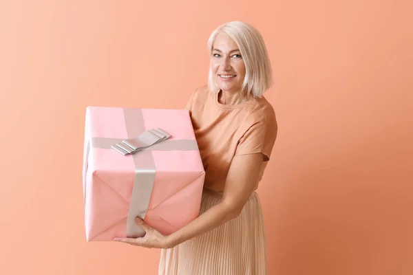 Ώριμη γυναίκα με κουτί δώρου στο χρώμα φόντο — Φωτογραφία Αρχείου