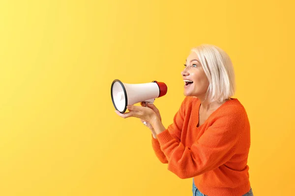Mature woman with megaphone on color background — Stock Photo, Image
