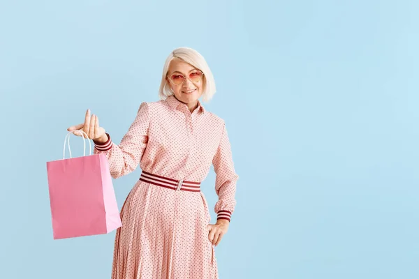 Stijlvolle rijpe vrouw met boodschappentas op kleur achtergrond — Stockfoto