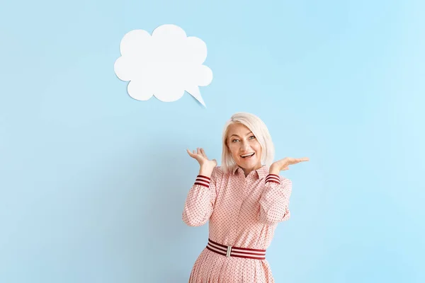 Mature woman with blank speech bubble on color background — Stock Photo, Image