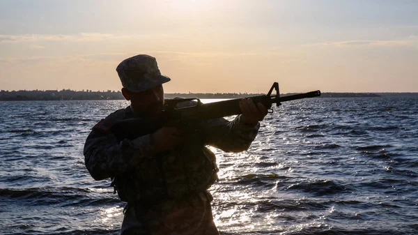 Silhouette di soldato in mimetizzazione prendendo di mira vicino al fiume — Foto Stock