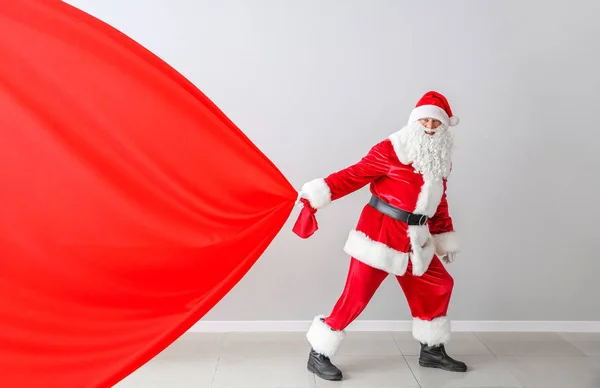 Santa Claus with big bag near light wall — Stock Photo, Image