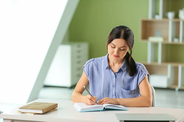 Beautiful young woman making notes at home — Stock Photo, Image