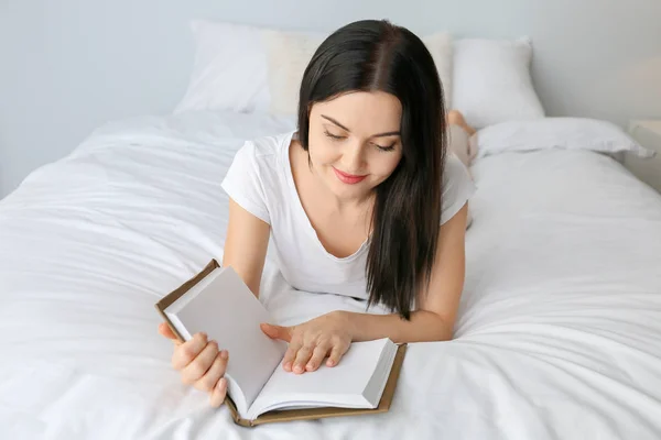 Hermosa joven leyendo libro en el dormitorio — Foto de Stock