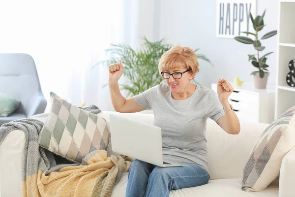 Mulher de meia-idade feliz com laptop em casa — Fotografia de Stock