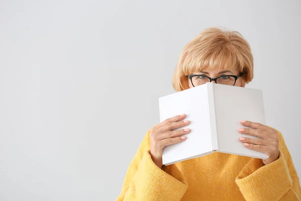 Hafif arka plan üzerinde kitap ile orta yaşlı kadın portresi — Stok fotoğraf