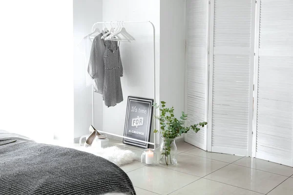 Stylish interior of bedroom with clothes hanger and eucalyptus branches — Stock Photo, Image