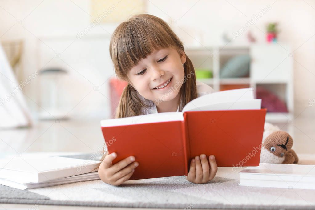 Cute little girl reading book at home