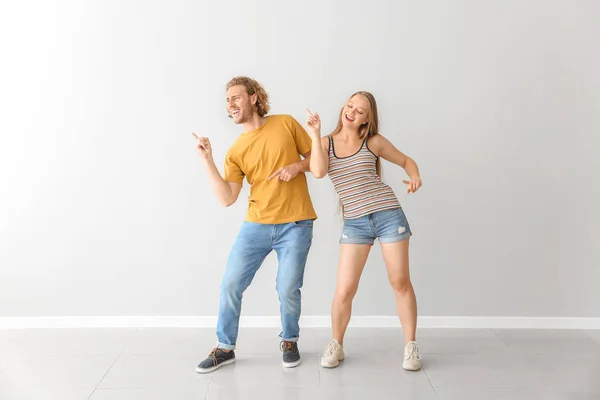 Cool pareja joven bailando contra la pared blanca — Foto de Stock