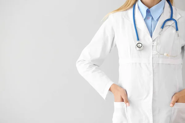 Vrouwelijke arts met stethoscoop op lichte achtergrond — Stockfoto