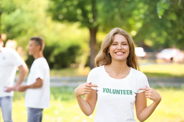Kobieta wolontariusz wskazując na jej t-shirt na zewnątrz — Zdjęcie stockowe