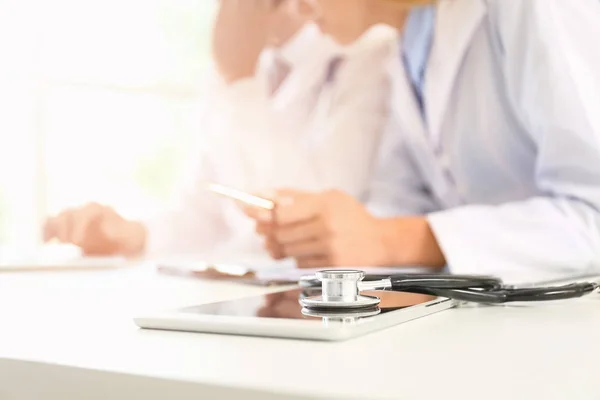 Tablet computer en stethoscoop op tafel in kliniek — Stockfoto