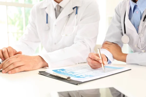 Mannelijke en vrouwelijke artsen werken aan tafel in kliniek — Stockfoto