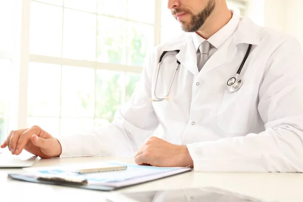 Médico varón sentado en la mesa de la clínica — Foto de Stock