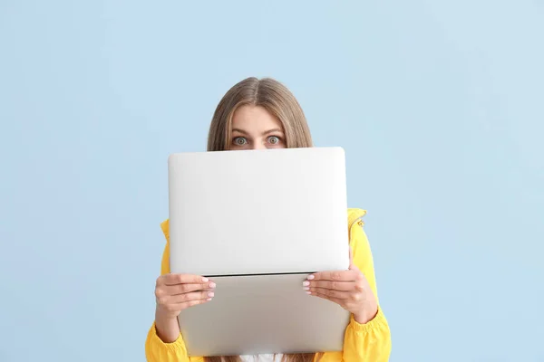 Verrast jonge vrouw met laptop op kleur achtergrond — Stockfoto