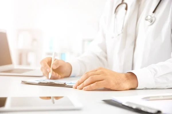 Mannelijke arts werkzaam aan tafel in kliniek — Stockfoto