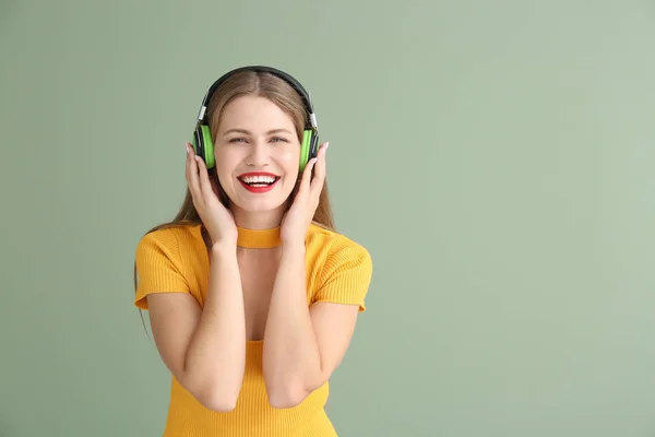 Mujer joven y feliz escuchando música sobre fondo de color — Foto de Stock