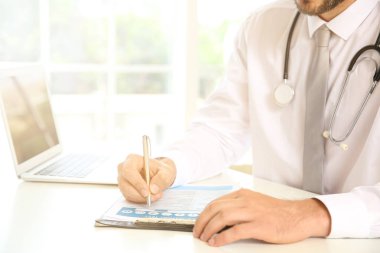 Klinikteki masada çalışan erkek doktor.