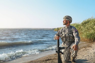 Nehir kenarında saldırı tüfeği ile Asker