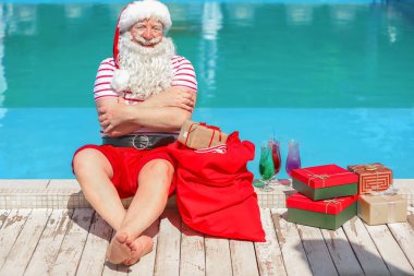 Tatil beldesinde yüzme havuzu yakınında hediyeler ile Noel Baba