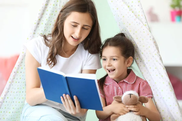 Söt liten flicka och hennes äldre syster läsning bok hemma — Stockfoto