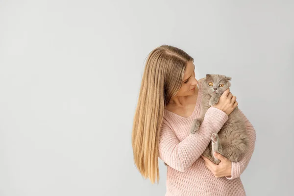 Beautiful woman with cute cat on light background — Stock Photo, Image