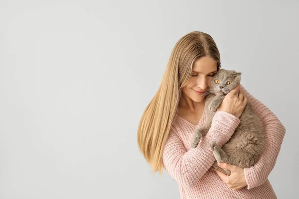 Gyönyörű hölgy aranyos macskával, világos háttérrel — Stock Fotó
