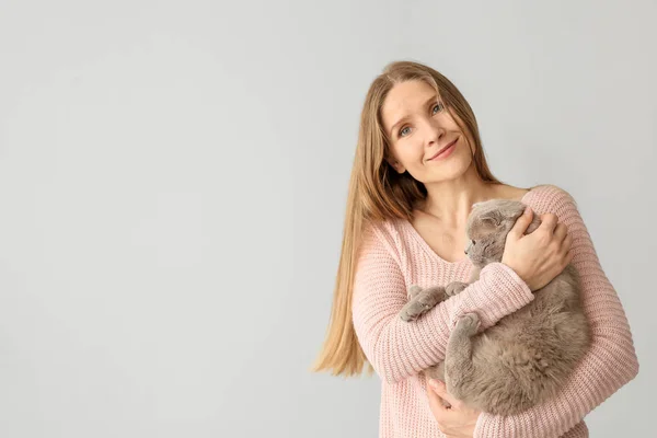 Beautiful woman with cute cat on light background — Stock Photo, Image