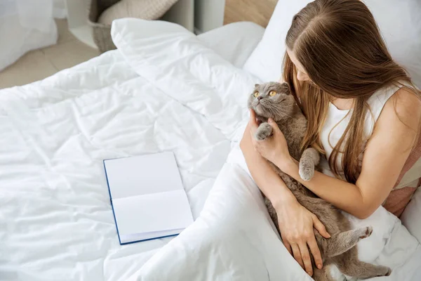 Beautiful woman with cute cat sitting in bed at home — Stock Photo, Image