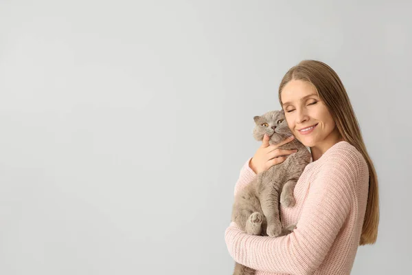 Beautiful woman with cute cat on light background — Stock Photo, Image