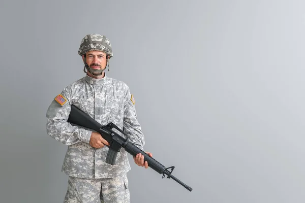 Soldier with assault rifle on grey background — Stock Photo, Image