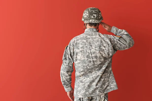 Saluting soldier on color background, back view — Stock Photo, Image