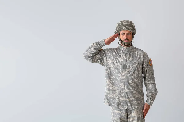 Saluting soldier on light background — Stock Photo, Image
