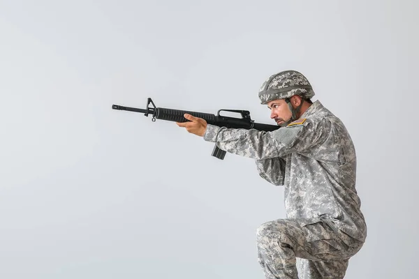 Soldier in camouflage taking aim on light background — Stock Photo, Image