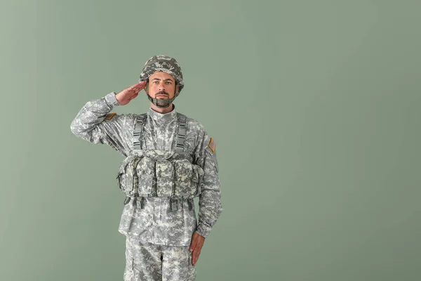 Saluting soldier on color background — Stock Photo, Image