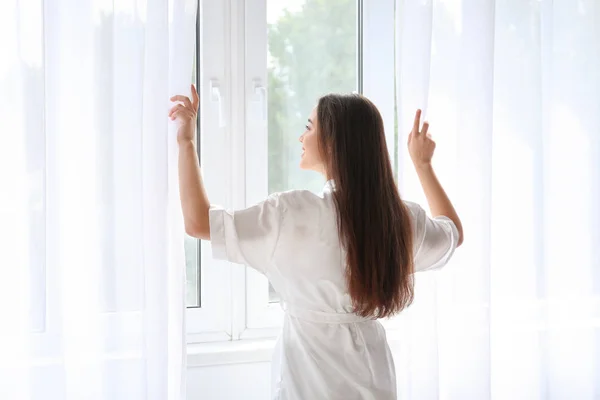 Morning of beautiful young woman opening curtains in room — Stock Photo, Image