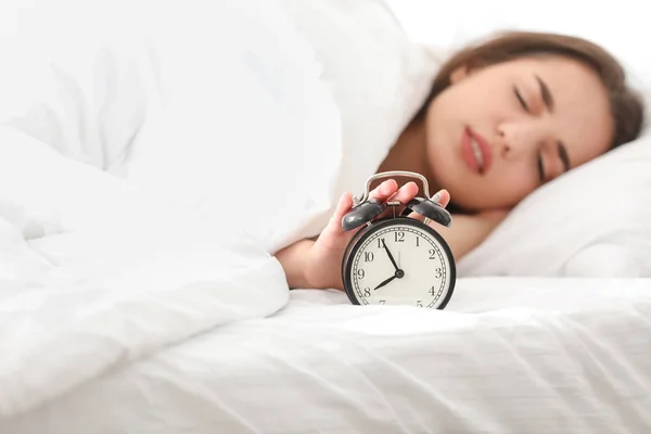 Reggel a gyönyörű fiatal nő alszik az ágyban ébresztőórával — Stock Fotó