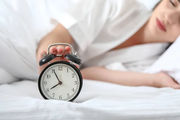 Sonnolenta giovane donna che spegne la sveglia al mattino — Foto Stock