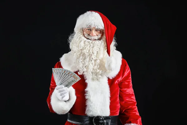 Санта-Клаус с деньгами на темном фоне — стоковое фото