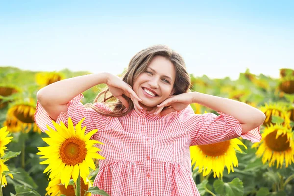 Beautiful young woman in sunflower field on summer day — Stock Photo, Image