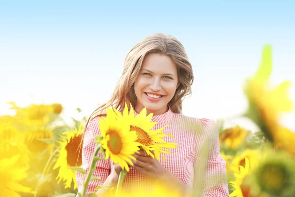 Beautiful young woman in sunflower field on summer day — Stock Photo, Image