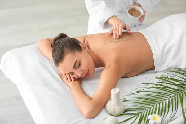 Jonge vrouw ondergaat een behandeling met bodyscrub in de spa salon — Stockfoto